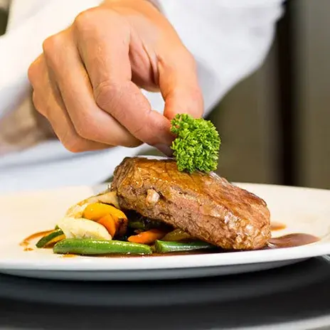 Wilshire Estates Chef Created Meals, chef garnishing a plate.