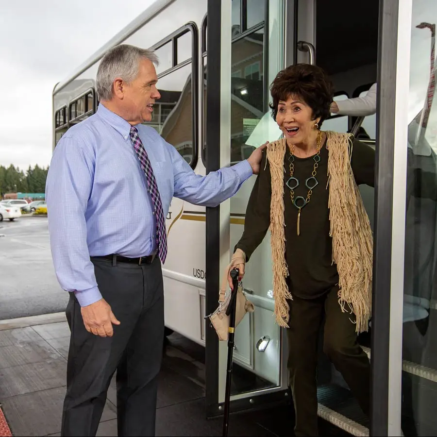 Wilshire Estates man helping lady off bus